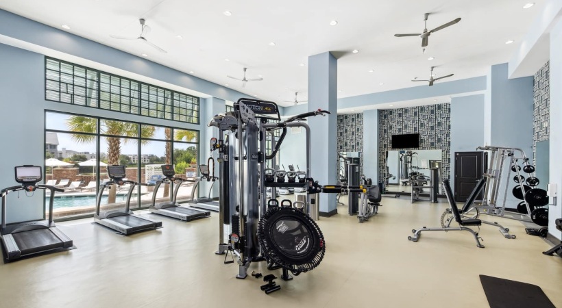 fitness center in a bright well-lit room showing plenty of equipment and modern decor in a large, spacious room