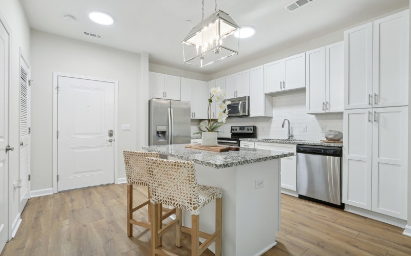 kitchen with stainless appliances, two tone cabinets, bar stools